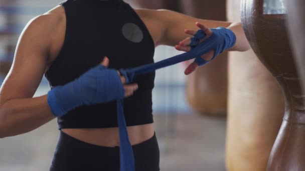 体操馆的女拳击手 在老式皮制冲床袋旁边用防护服包住双手 动作缓慢 — 图库视频影像