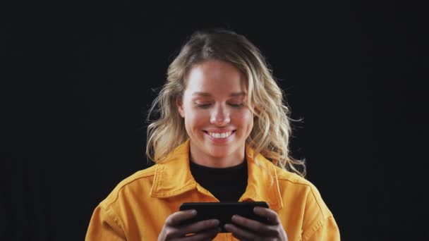 Молодая Женщина Улыбается Смотрит Контент Транслируемый Мобильный Телефон Фоне Черной — стоковое видео