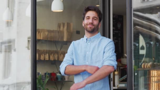 外に立ってカメラで微笑む喫茶店の男性オーナーの肖像 スローモーションで撮影 — ストック動画