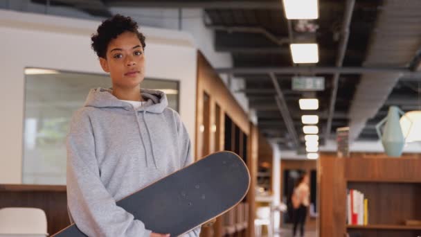 現代のオープンプランオフィスでスケートボードに取り組むために通勤しているカジュアルな服装の若いビジネスマンの肖像画 スローモーションで撮影 — ストック動画