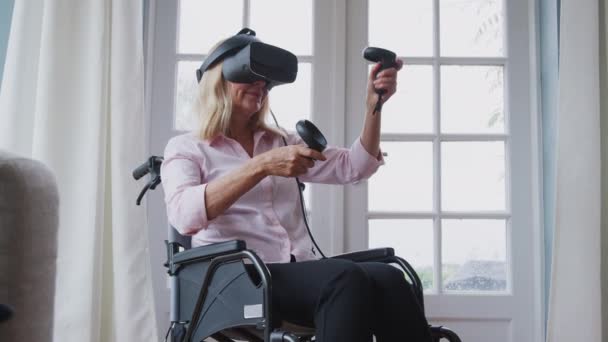 成熟した障害のある女性車椅子で自宅で仮想現実ヘッドセットを着てゲームを保持コントローラをプレイ スローモーションで撮影 — ストック動画