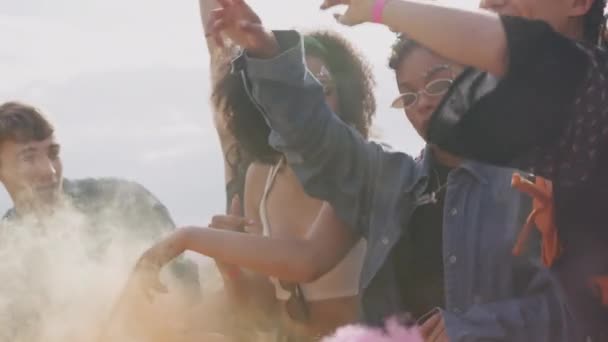 一群年轻的朋友在音乐节现场的障碍物后面跳舞 他们带着烟雾 慢动作地发射信号弹 — 图库视频影像