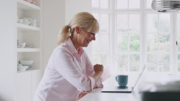 成熟した女性に家庭でビデオ通話を使用してノートパソコンでキッチンカウンター 遅い動きで撮影 — ストック動画