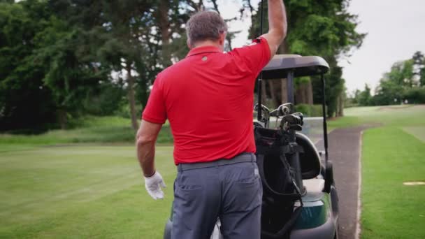 成熟した男性のゴルファーはティーにゴルフボールを置く前にバギー上の袋からクラブを選択 スローモーションで撮影 — ストック動画