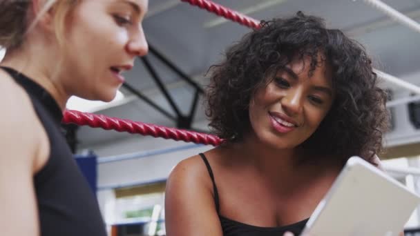 ボクシングリングによってデジタルタブレット上で女性ボクサーチェック運動性能を持つ女性パーソナルトレーナー スローモーションで撮影 — ストック動画
