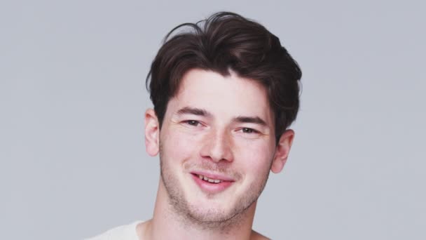 Joven Mirando Cámara Sonriendo Contra Fondo Blanco Del Estudio Filmado — Vídeos de Stock