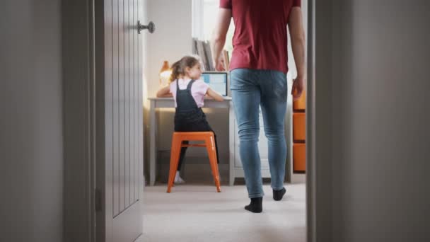父はドアや膝を通って娘を助けるために歩きますラップトップを使用してベッドルームで机 遅い動きで撮影 — ストック動画