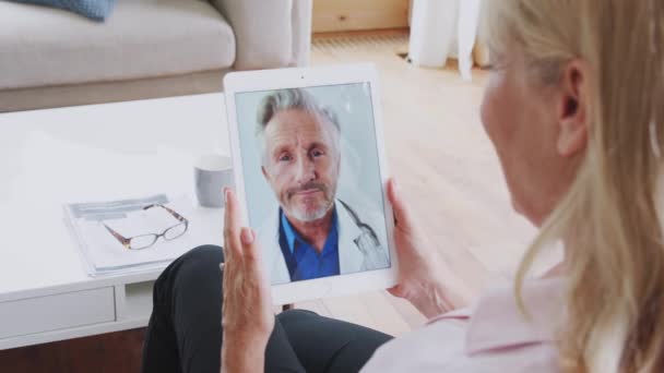 デジタルタブレットを使用して自宅で医師とオンライン医療相談を持っている熟女 スローモーションで撮影 — ストック動画