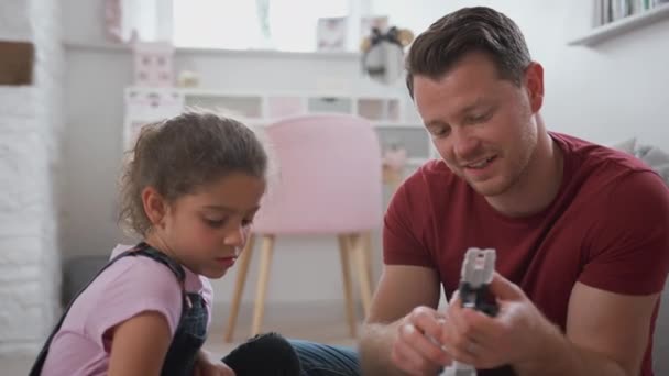 Vater Mit Tochter Sitzt Auf Schlafzimmerboden Und Baut Roboter Aus — Stockvideo