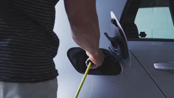 男はトランクを開く前に電気自動車に充電ケーブルを取り付け 再利用可能なショッピングバッグを取り出す スローモーションで撮影 — ストック動画
