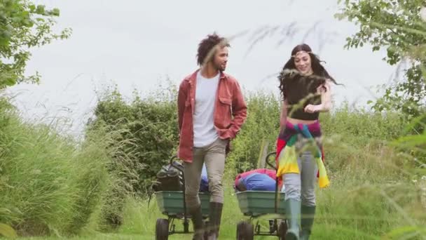 Young Couple Pulling Trolley Filled Camping Equipment Field Music Festival — Stockvideo