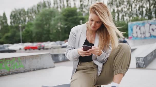 도회지 스케이트 공원에 여자가 휴대폰으로 메시지와 미디어를 확인하는 동작으로 — 비디오
