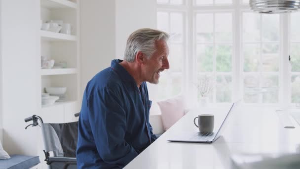 Älterer Behinderter Mann Rollstuhl Hause Telefoniert Mit Laptop Auf Küchentheke — Stockvideo