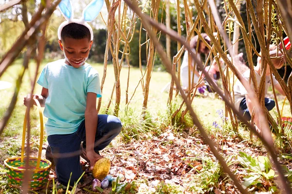 バニーの耳をしている子供たちのグループ庭に隠されたイースターエッグを見つける — ストック写真