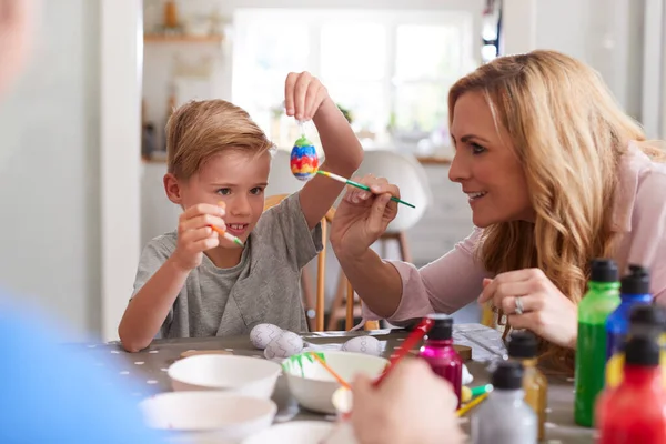 Mor Med Søn Sidder Ved Bordet Udsmykning Til Påske Derhjemme - Stock-foto