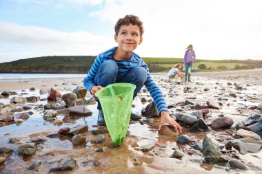 Children Looking In Rockpools On Winter Beach Vacation clipart