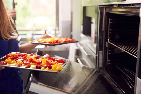 厨房里穿着四季豆的妇女的近照 把辣椒盘放在烤箱里烤 — 图库照片