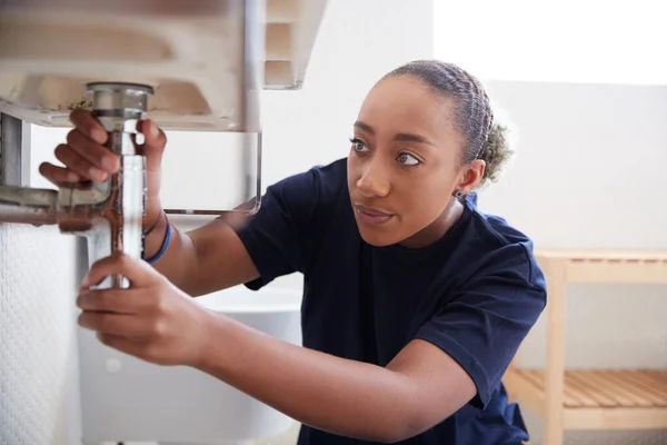 家庭用バスルームで漏れのシンクを修正するために働く女性配管工 — ストック写真
