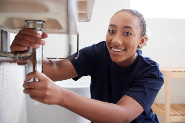 自宅のバスルームで漏れのシンクを修正するために働く女性配管工の肖像 — ストック写真
