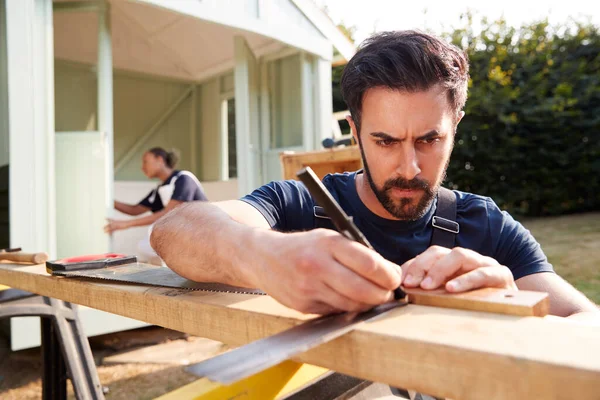 Carpintero Masculino Con Aprendiz Femenino Midiendo Madera Para Construir Casa —  Fotos de Stock