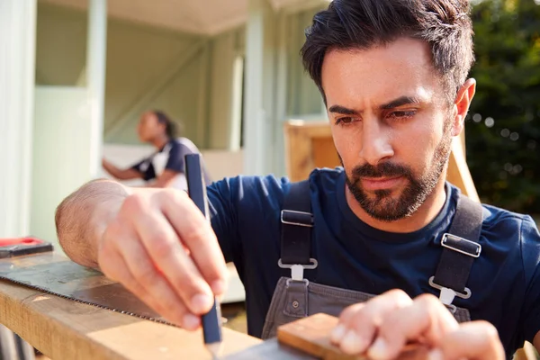 Carpintero Masculino Con Aprendiz Femenino Midiendo Madera Para Construir Casa — Foto de Stock