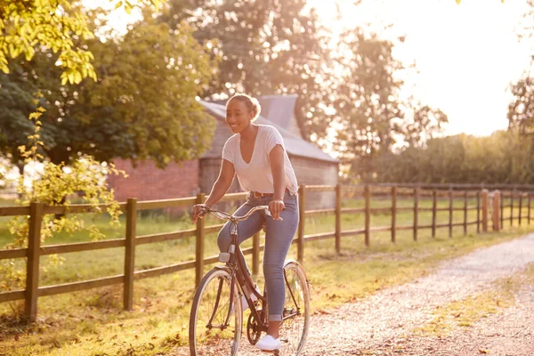 Ung Kvinna Ridcykel Längs Country Lane Vid Solnedgången — Stockfoto