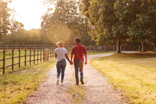 Vista Trasera Pareja Romántica Caminando Mano Largo Country Lane Atardecer —  Fotos de Stock