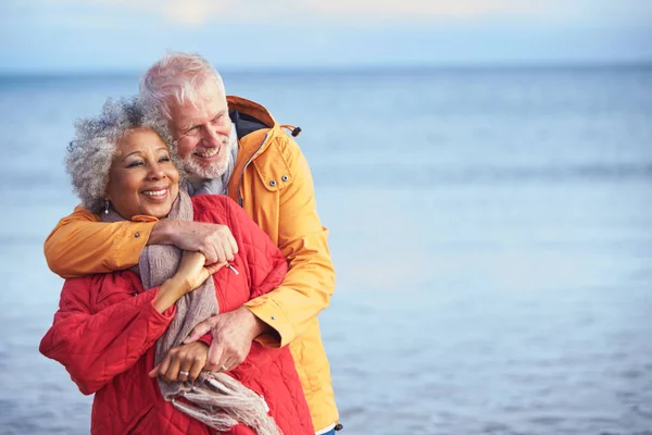 Houden Van Senior Paar Knuffelen Als Lopen Langs Kustlijn Winter — Stockfoto