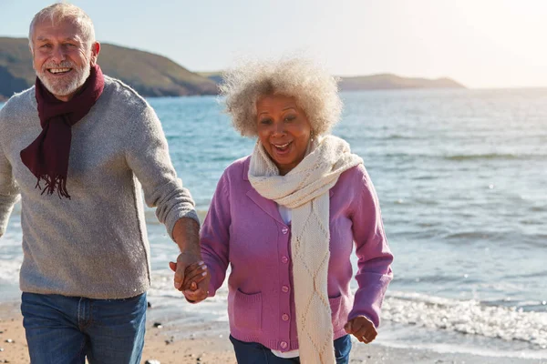 Activo Senior Couple Running Winter Beach Waves Holding Hands — Foto de Stock