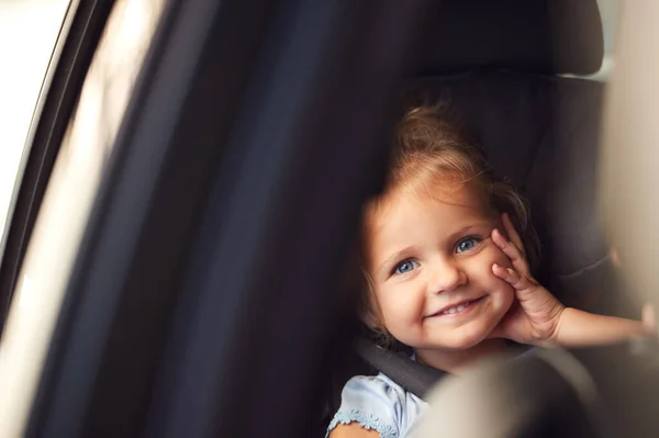 車の旅で子供の安全シートに座っている若い女の子の肖像画窓の外を見る — ストック写真