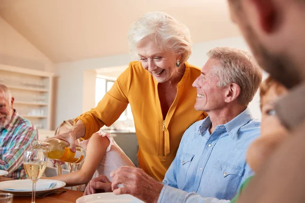 Grootmoeder Gieten Wijn Als Multi Generatie Familie Zitten Rond Tafel — Stockfoto