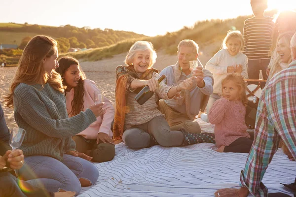 冬のビーチでの休暇を祝うために多世代の家族のオープニングとシャンパンを注ぐ — ストック写真