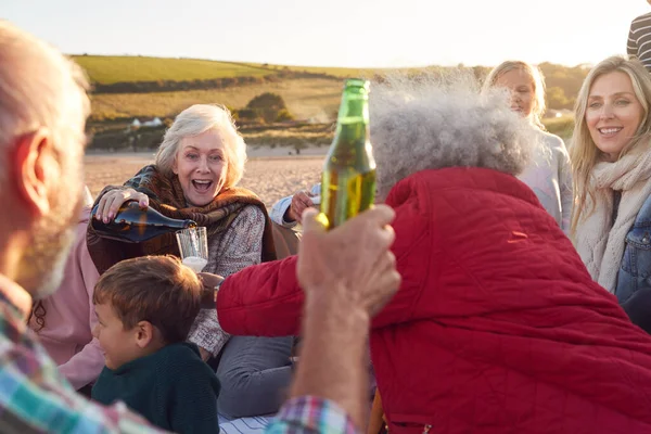 冬のビーチでの休暇を祝うために多世代の家族のオープニングとシャンパンを注ぐ — ストック写真