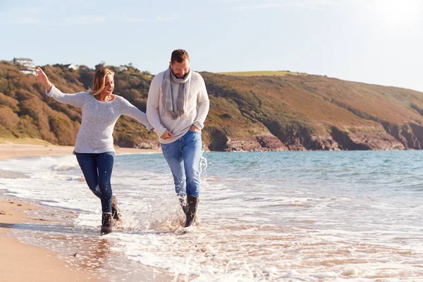 Älskade Par Håller Händer När Går Längs Strandlinjen Genom Vågorna — Stockfoto