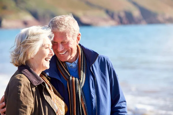 Kochająca Starsza Para Przytulająca Się Podczas Spaceru Wzdłuż Wybrzeża Plaży — Zdjęcie stockowe