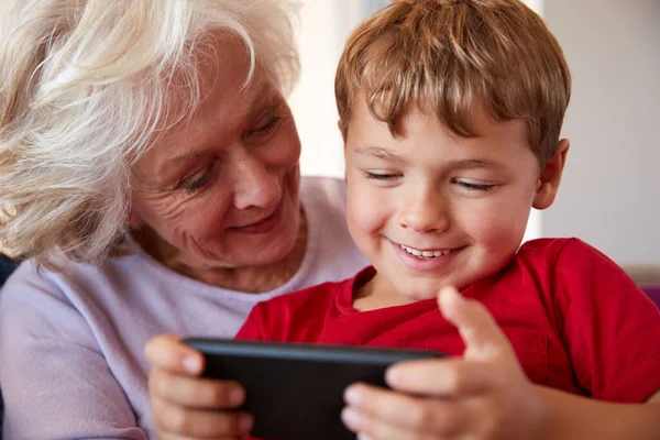 おばあちゃんが自宅で携帯電話で孫とビデオゲームをプレイ — ストック写真