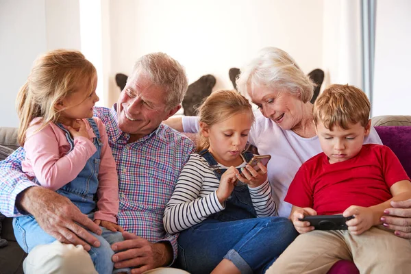 Dziadkowie Grający Gry Wideo Wnukami Telefonach Komórkowych Domu — Zdjęcie stockowe