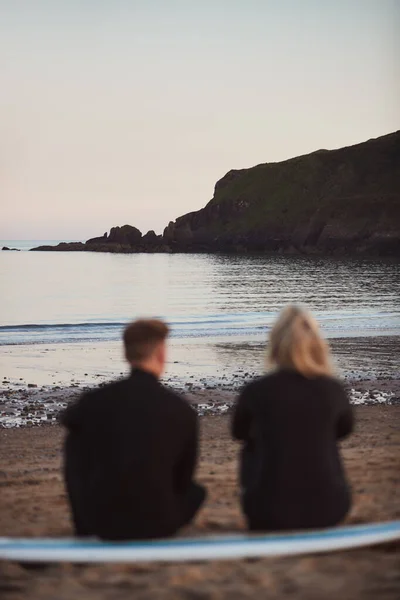 Defocused Shot Couple Wetsuits Surfing Staycation Sitting Surfboard Looking Out — Stock Photo, Image