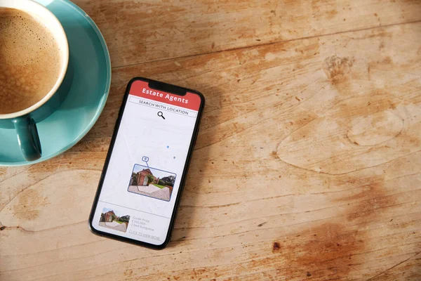 Close Up Of Mobile Phone With Realtors Property App Lying On Table