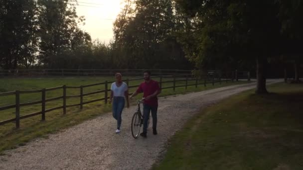 Drone Disparo Pareja Empujando Bicicleta Largo Pista Campo Atardecer — Vídeo de stock