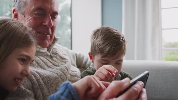 Abuelo Casa Con Nietos Divirtiéndose Jugando Videojuegos Teléfono Móvil Filmado — Vídeo de stock