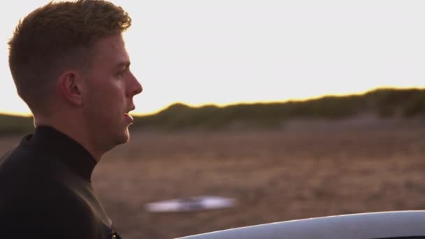 Joven Traje Neopreno Pie Playa Atardecer Sosteniendo Tabla Surf Las — Vídeo de stock