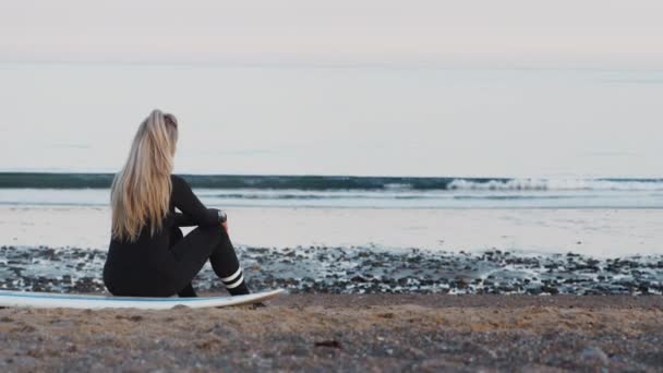 Dalgıç Kıyafetli Bir Kadının Gün Batımında Sörf Tahtasına Oturup Okyanusa — Stok video