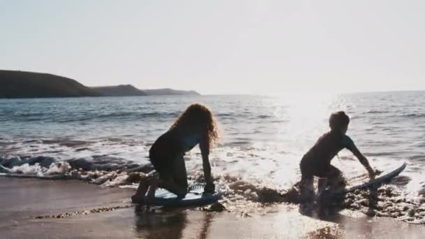 2人の子供が夏のビーチ休暇にボディボードで波で遊ぶウェットスーツを着て スローモーションで撮影 — ストック動画