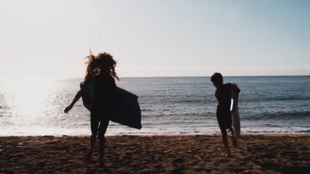 夏のビーチ休暇にボディボードで波に実行されているウェットスーツを着て2人の子供の後部ビュー スローモーションで撮影 — ストック動画