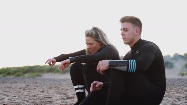 Paar Wetsuits Dragen Zittend Surfplank Uitkijkend Oceaan Voordat Opstaan Langs — Stockvideo