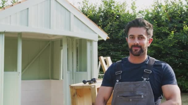 庭で木製の夏の家を構築する男性大工の肖像 スローモーションで撮影 — ストック動画