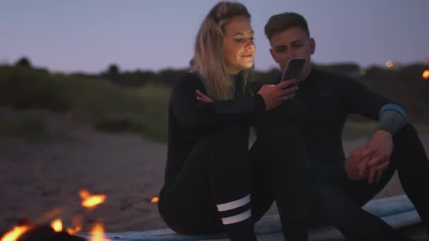 Paar Sommerurlaub Sitzt Lagerfeuer Strand Und Benutzt Handy Während Die — Stockvideo