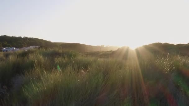 ウェールズの砂丘に沈む美しい夜の太陽のドローンショット — ストック動画