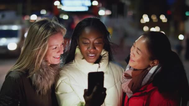 城市街道上的一群女性朋友在晚上用手机应用程序订出租车 慢镜头拍摄 — 图库视频影像